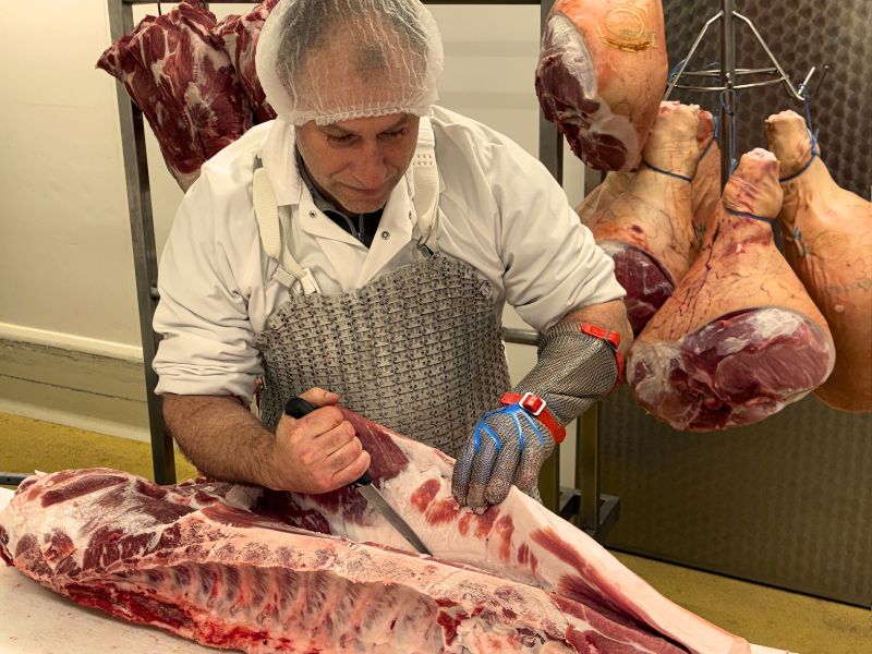 Charcuterie Cabrol la salvetat sur agout Homme qui découpe un morceau de viande